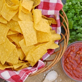 Homemade Tortilla Chips in a basket with salsa and cilantro