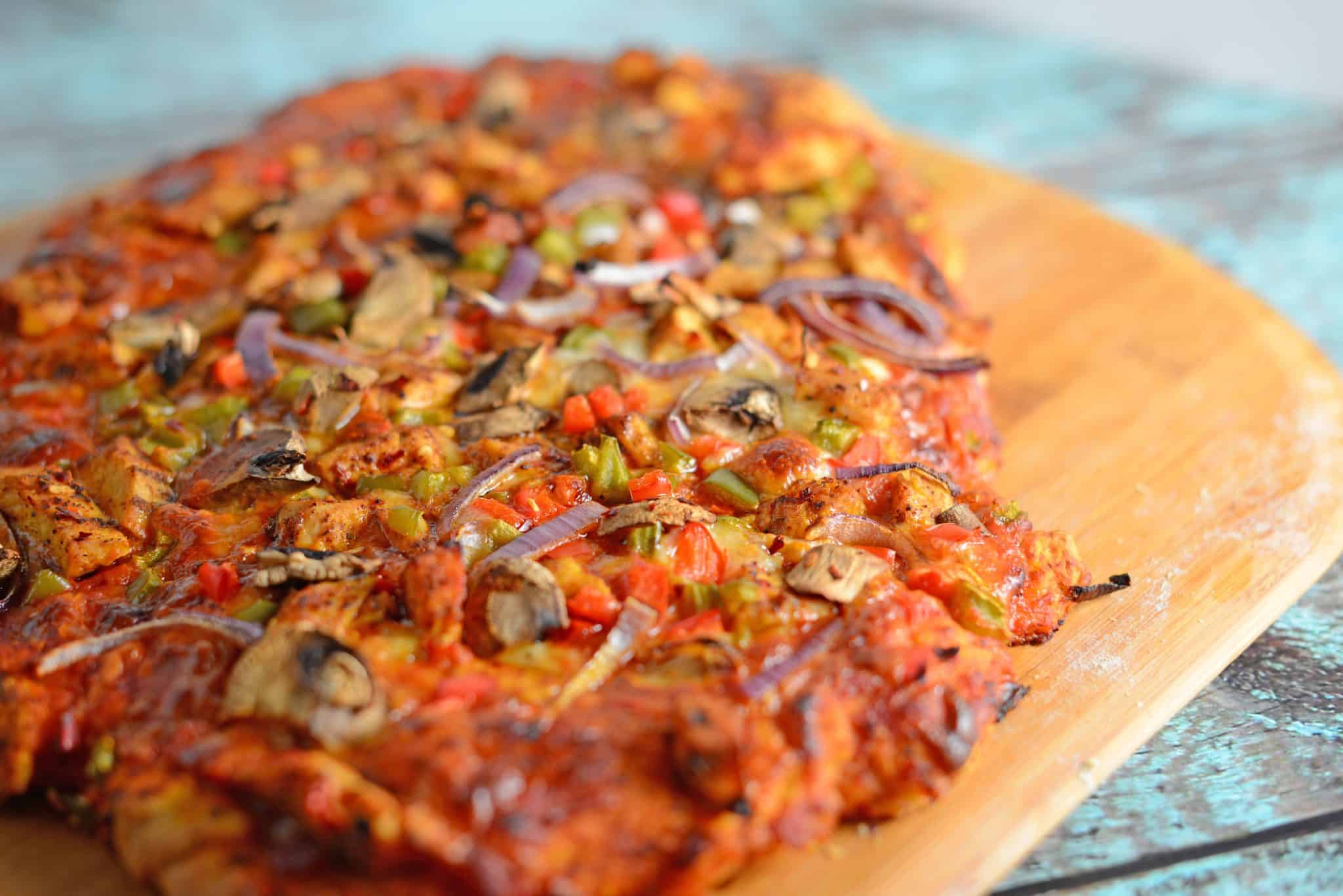 Caribbean Jerk Chicken Pizza is an easy homemade pizza recipe using spicy chicken, fresh vegetables and a touch of honey. #homemadepizza #jerkchicken #jerkchickenpizza www.savoryexperiments.com 