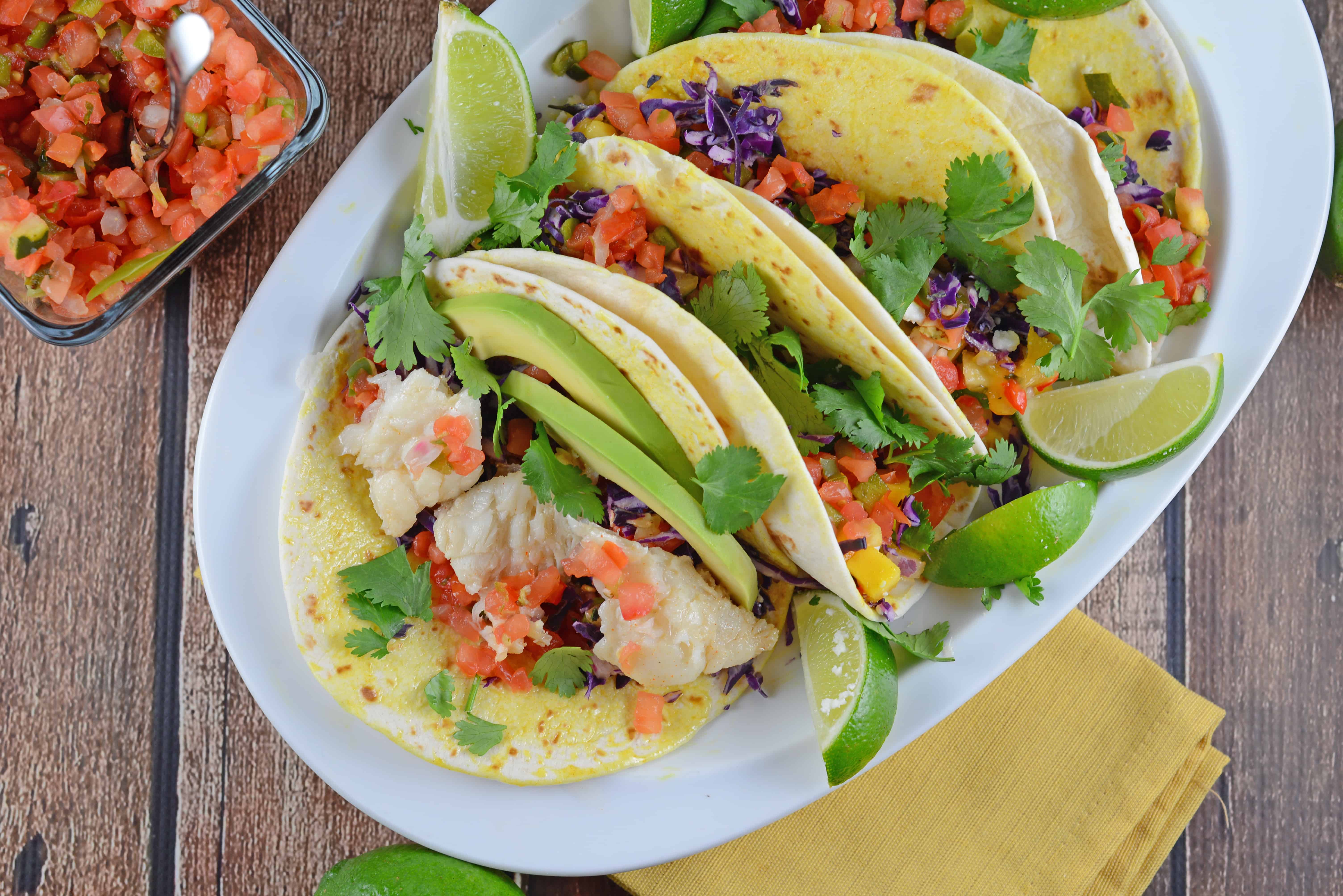 Easy fish taco recipe full of flavor with pico de gallo, shredded cabbage, avocado, queso fresco and a special homemade hot sauce. #fishtacorecipe #bestfishtacos www.savoryexperiments.com