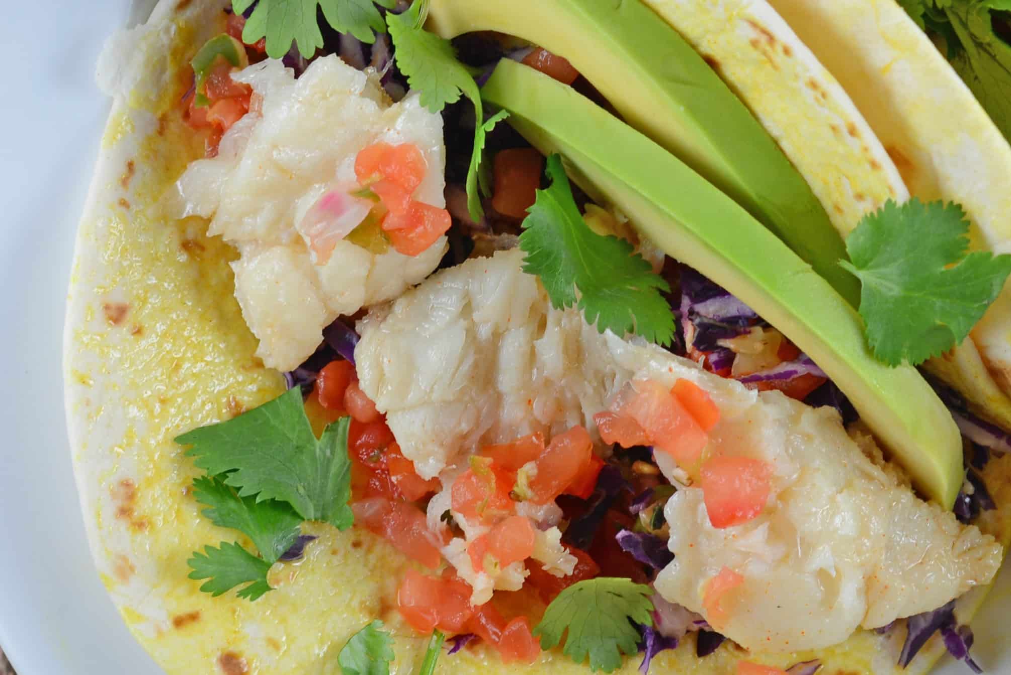 Easy fish tacos full of flavor with pico de gallo, shredded cabbage, avocado, queso fresco and a special homemade hot sauce. #fishtacos #tacorecipes www.savoryexperiments.com 