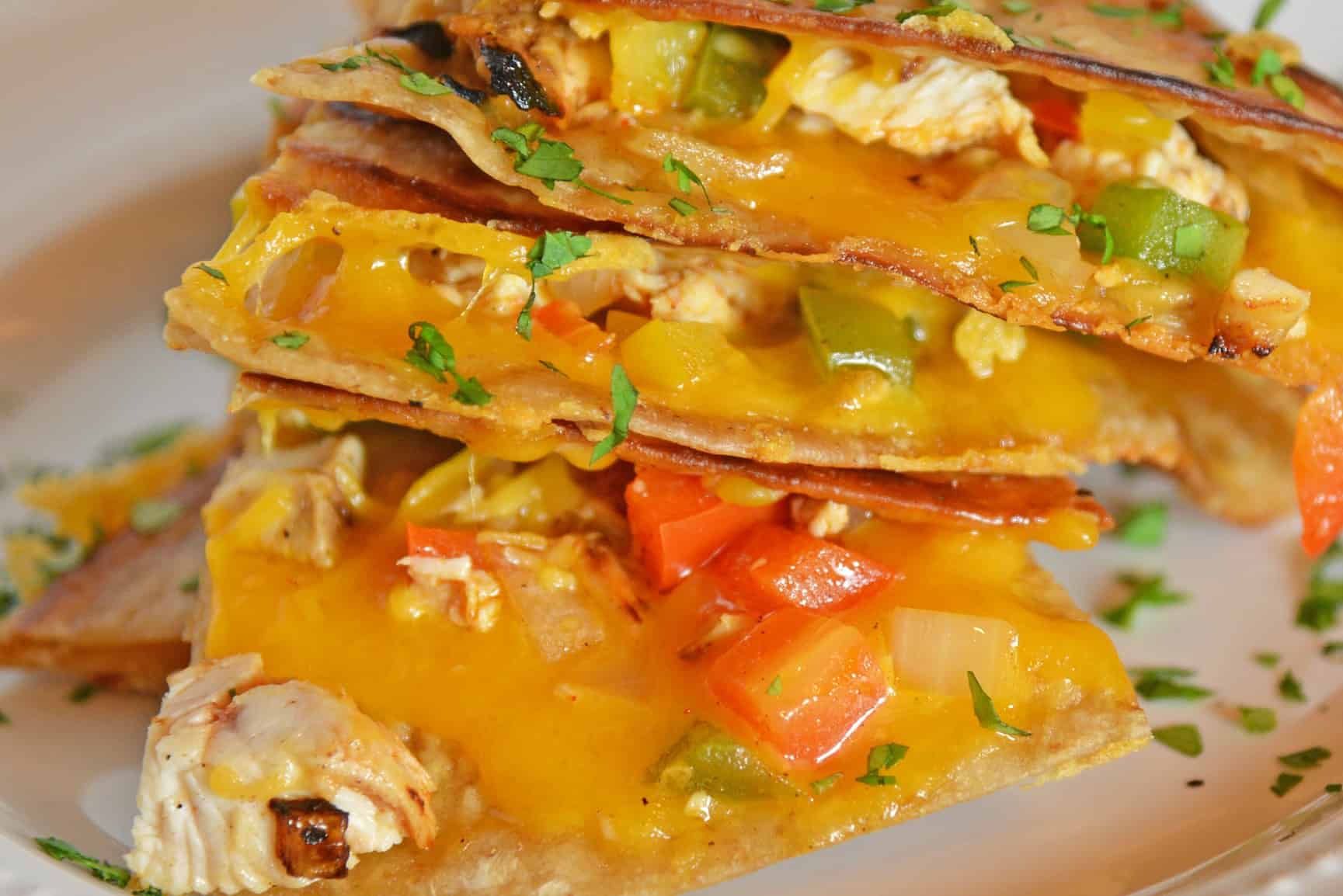 This Chicken Quesadillas Recipe is made with crispy tortillas, chopped vegetables and lots of cheese! This shows you how to make quesadillas the easy way! #chickenquesadillarecipe #howtomakechickenquesadillas www.savoryexperiments.com