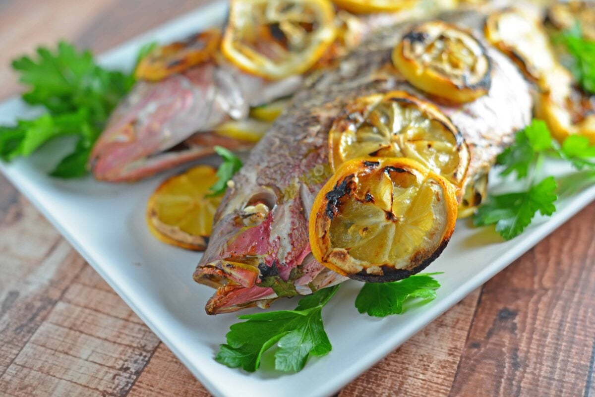 Red snapper fish on a white serving platter. 