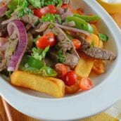 Lomo Saltado is a Peruvian dish using tender steak, onions, tomatoes, bell peppers and jalapenos over crispy French fries.
