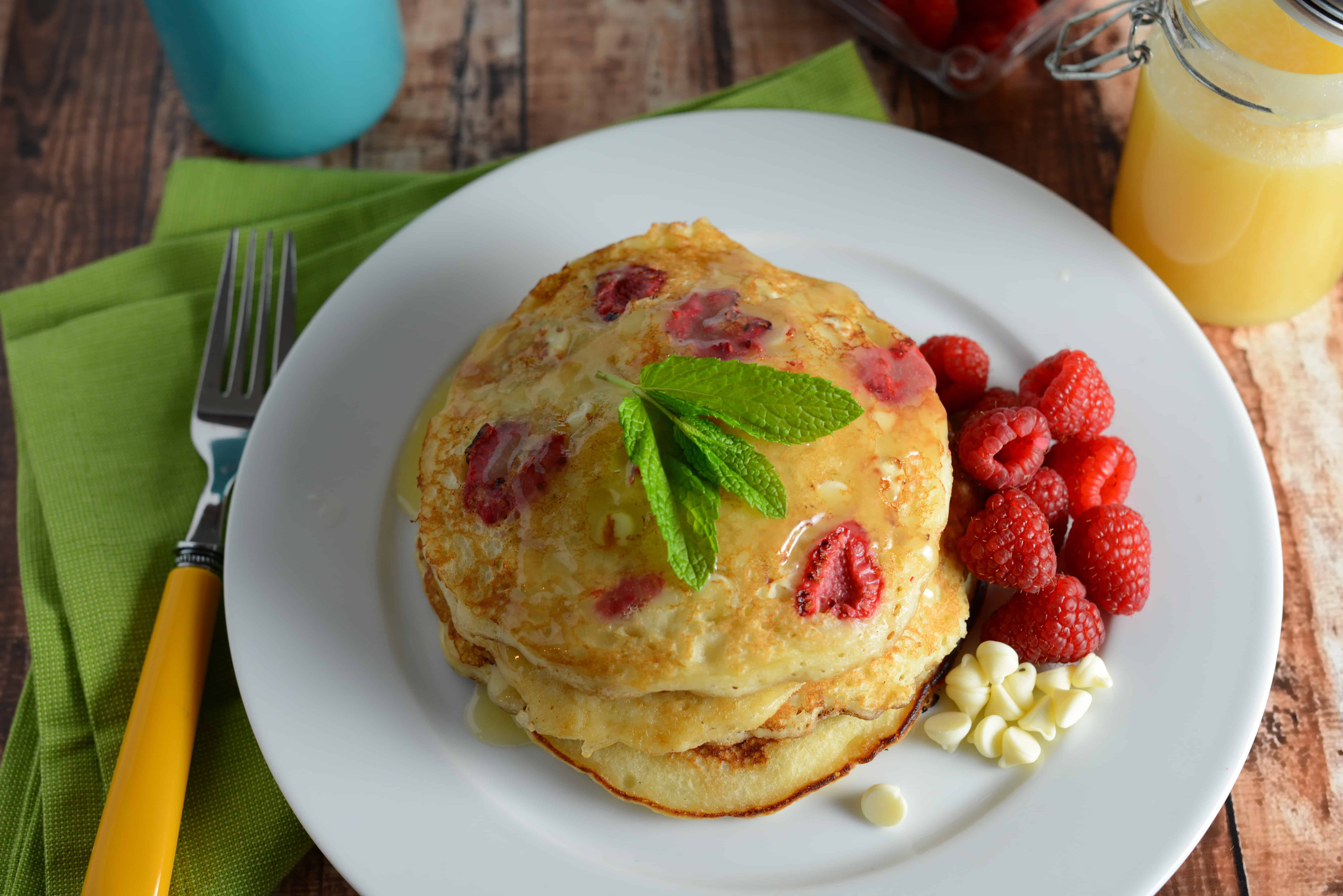 White Chocolate and Raspberry Pancakes Recipe - The perfect fluffy buttermilk pancakes dotted with fresh raspberries, white chocolate chips and homemade Dutch honey syrup. www.savoryexperiments.com