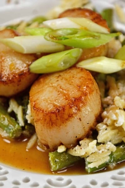 Orange Caramel Scallops are an easy recipe that brings the feel of the restaurant right to your home! Scallops covered in a sticky, sweet orange caramel sauce! #scallopsrecipe #seascallopsversusbayscallops www.savoryexperiments.com