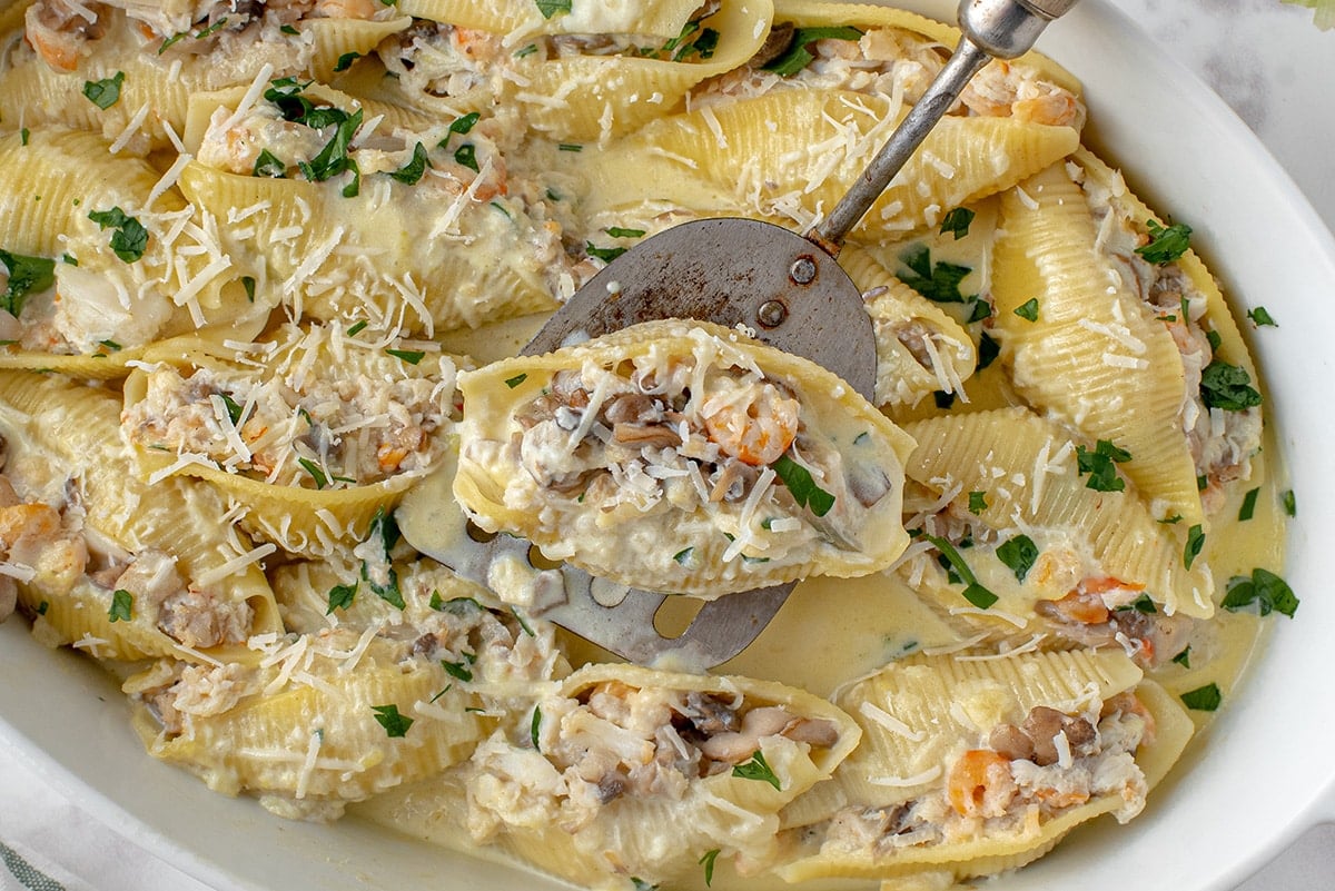 close up of a seafood stuffed shell on a spatula 