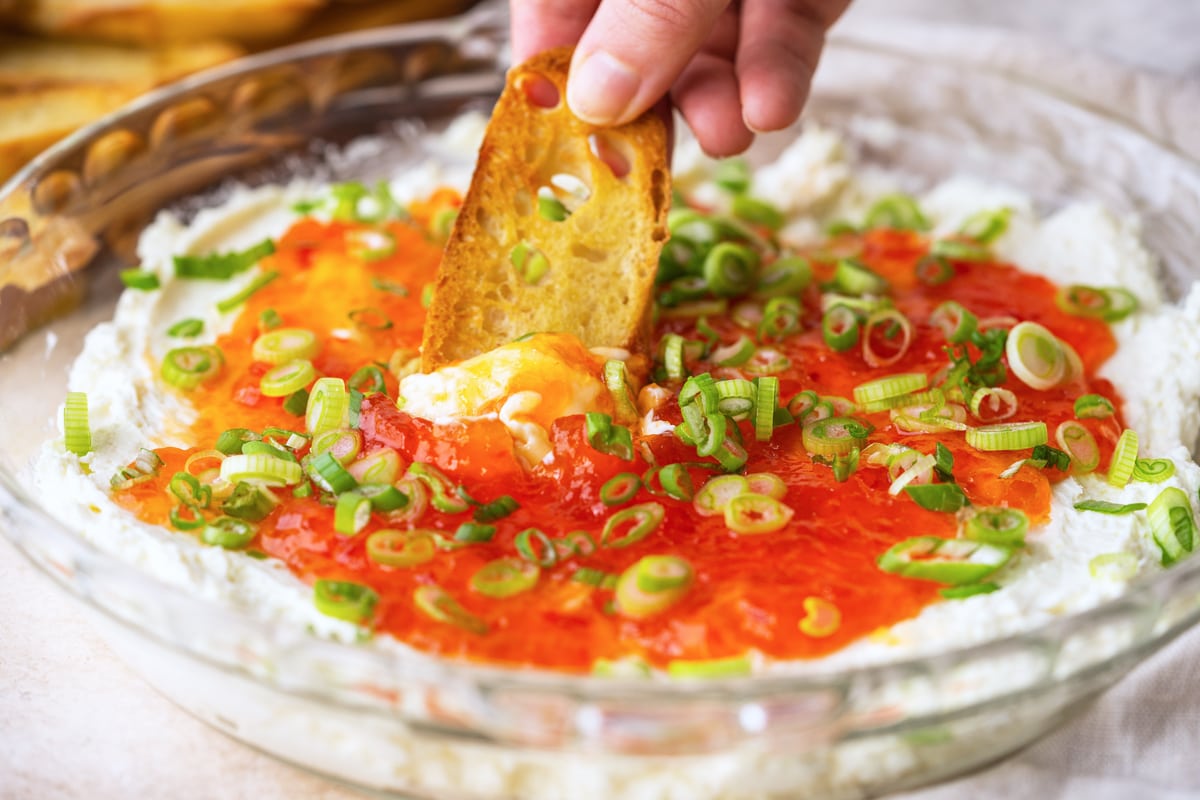 dipping a crostini in goat cheese dip