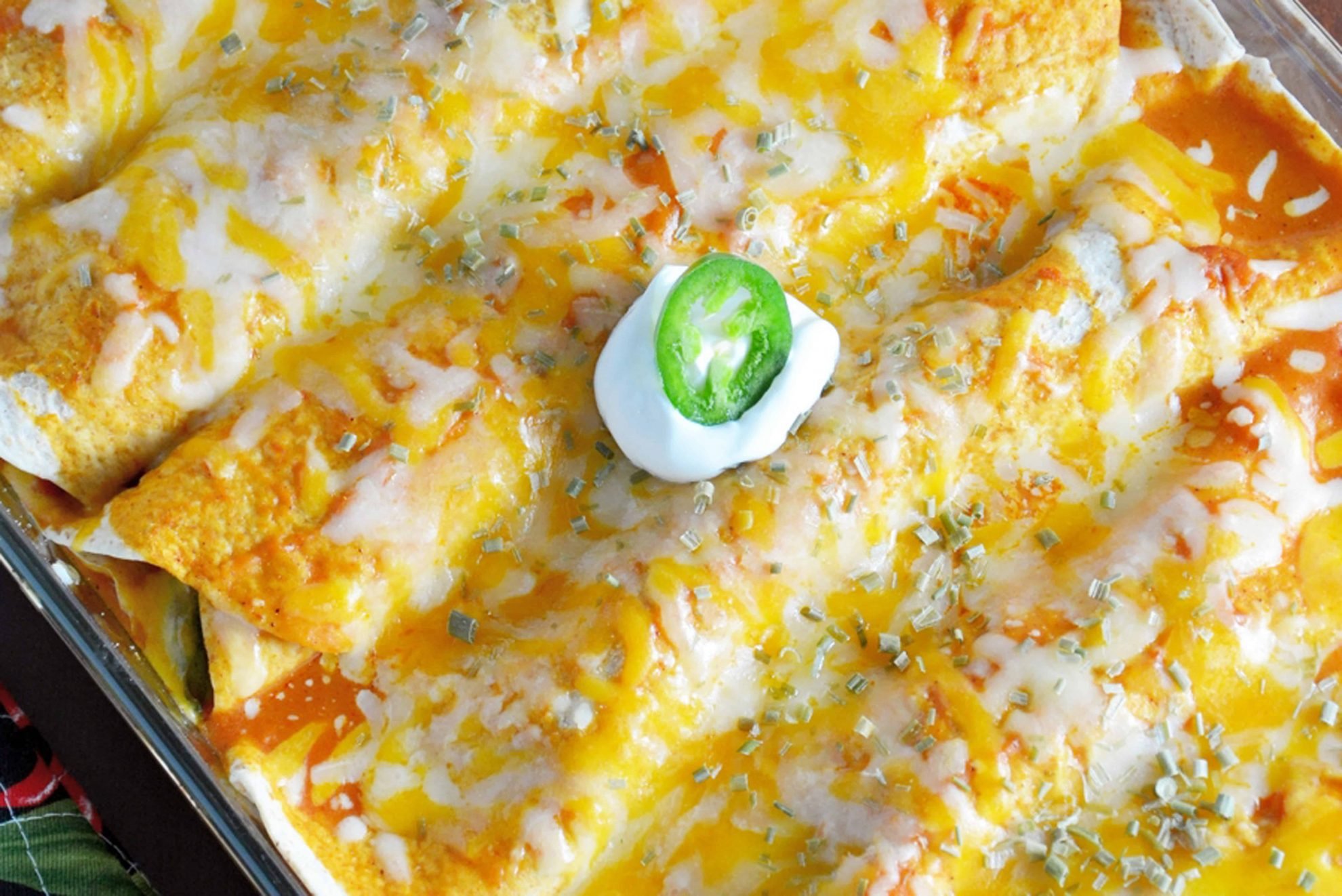 Baked Chicken Enchiladas with a dollop of sour cream in a baking dish