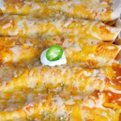 Close up of baked chicken enchiladas in a glass baking dish
