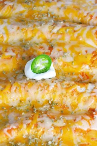 Close up of baked chicken enchiladas in a glass baking dish