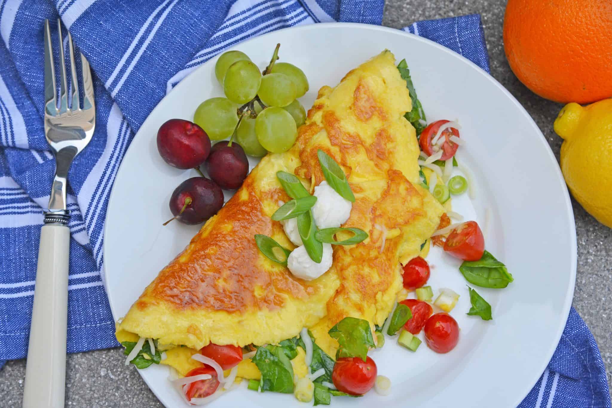 A Shrimp Omelette is a savory omelette with shrimp, scallions, spinach, tomatoes and fresh mozzarella cheese. A perfect recipe for those of us who love brunch! #shrimpomelette #omeletterecipes www.savoryexperiments.com