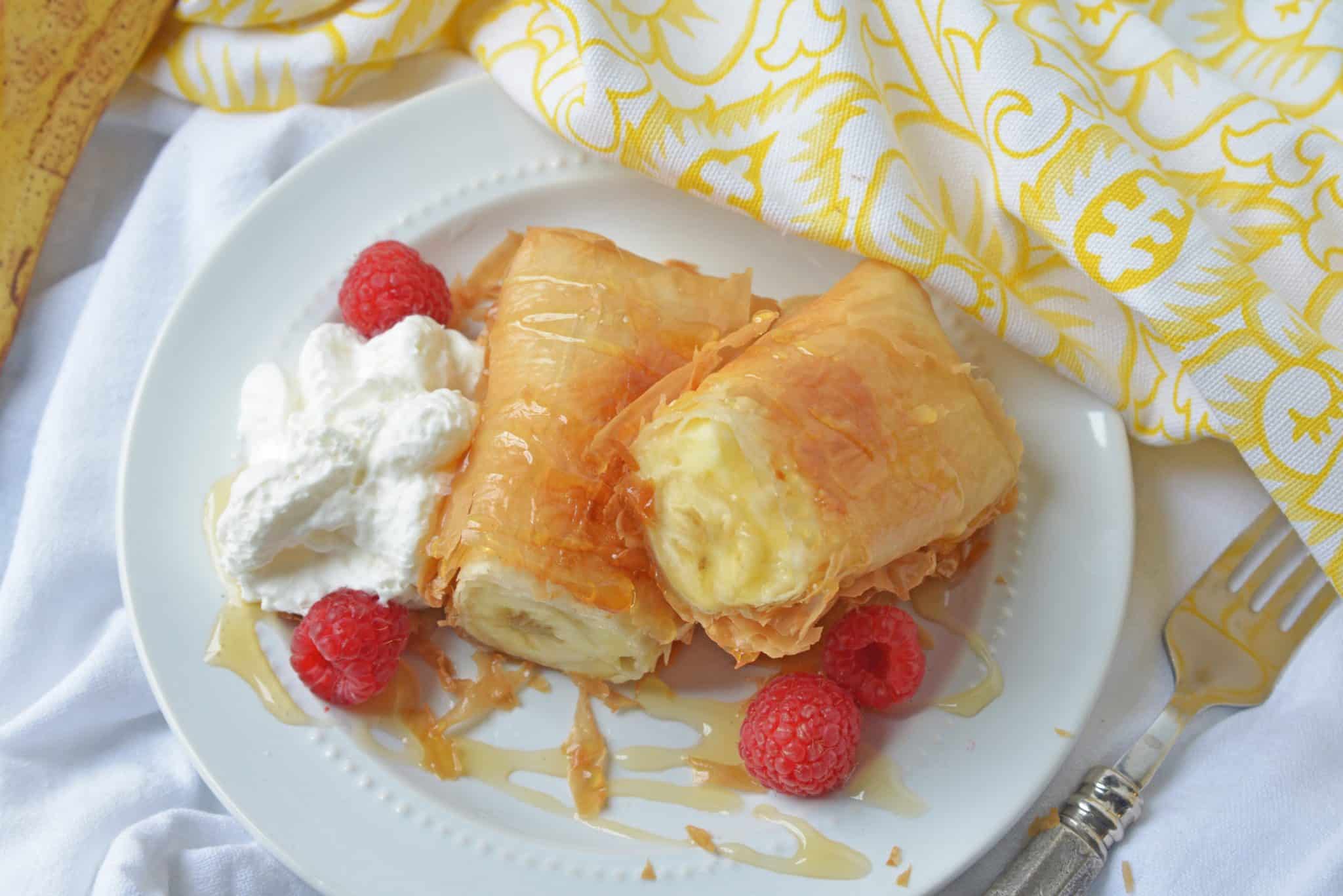 This Banana Fried Cheesecake recipe will become one of your all time favorite desserts! They are fried golden brown to perfection and drizzled with honey. #friedcheesecake #bananaspringrolls www.savoryexperiments.com
