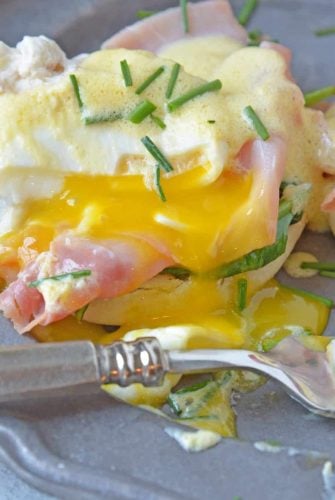 Simple Eggs Benedict tops toasted English muffins with wilted spinach, Canadian bacon, perfectly poached eggs and easy hollandaise sauce.  #eggsbenedictrecipe #easyeggsbenedict www.savoryexperiments.com