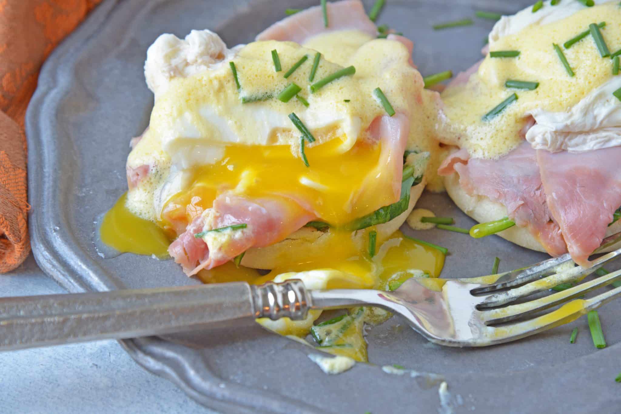 Simple Eggs Benedict tops toasted English muffins with wilted spinach, Canadian bacon, perfectly poached eggs and easy hollandaise sauce.  #eggsbenedictrecipe #easyeggsbenedict www.savoryexperiments.com 