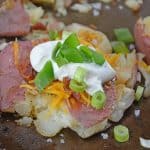 Loaded Smashed Potatoes are a cross between a loaded baked potato and loaded mashed potatoes. Topped with a zesty butter sauce, cheese, bacon, sour cream and scallions. #smashedpotatoes #potatorecipes www.savoryexperiments.com