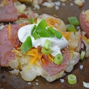 Loaded Smashed Potatoes are a cross between a loaded baked potato and loaded mashed potatoes. Topped with a zesty butter sauce, cheese, bacon, sour cream and scallions. #smashedpotatoes #potatorecipes www.savoryexperiments.com