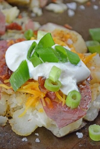 Loaded Smashed Potatoes are a cross between a loaded baked potato and loaded mashed potatoes. Topped with a zesty butter sauce, cheese, bacon, sour cream and scallions. #smashedpotatoes #potatorecipes www.savoryexperiments.com