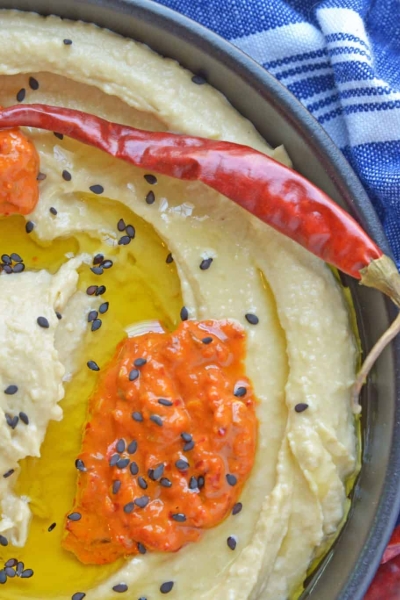 Harissa Hummus is an easy, packed full of flavor, homemade hummus recipe. Pair with vegetables or chips for a dip, or even as a spread on flatbreads or sandwiches! #spicyhummus #homemadehummusrecipe www.savoryexperiments.com