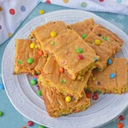 Thick and chewy M&M Cookie Bars are perfect for your cookie exchange, dessert potluck or an after school snack using just a few ingredients! #cookiebars #easydessertrecipes www.savoryexperiments.com