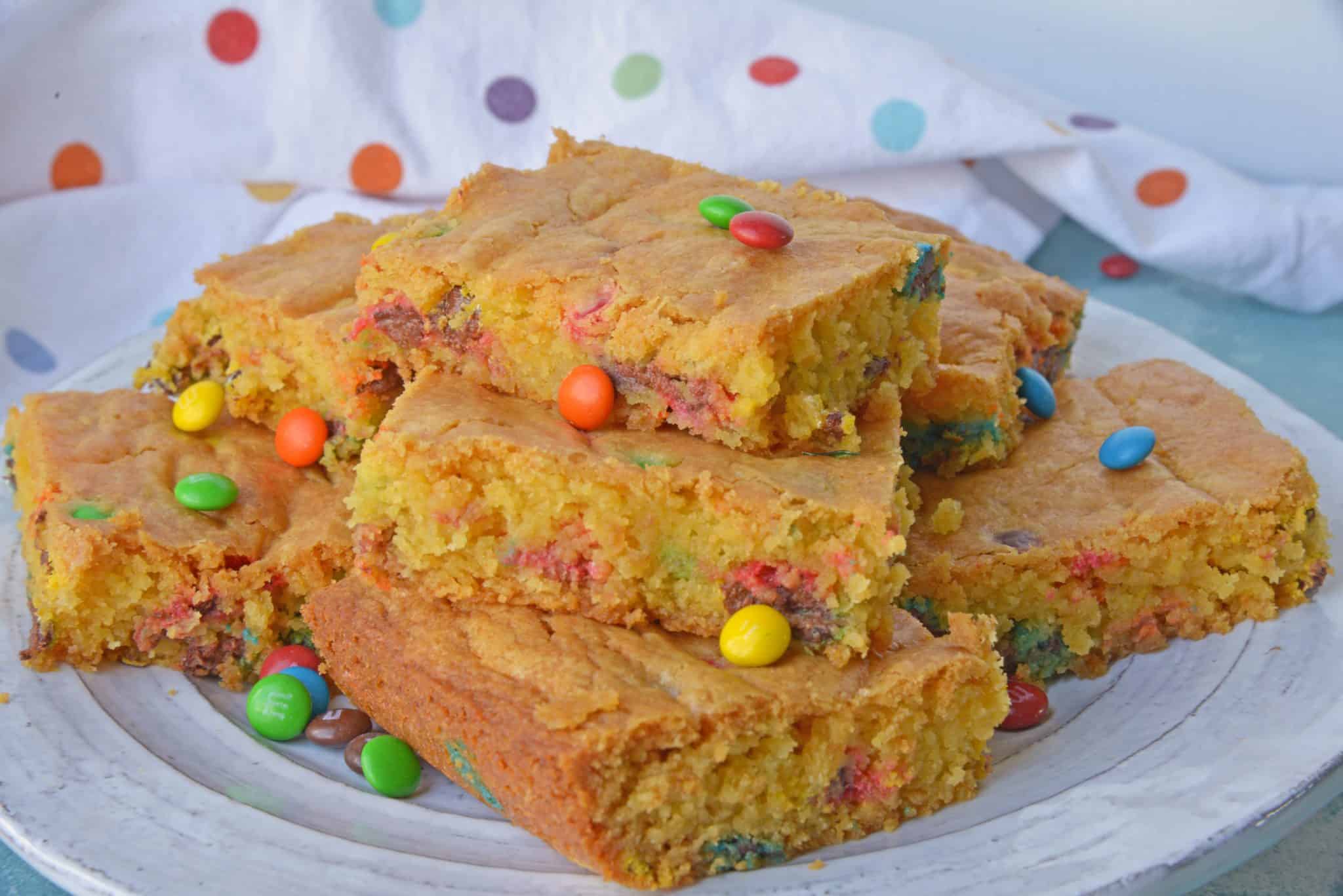 Thick and chewy M&M Cookie Bars are perfect for your cookie exchange, dessert potluck or an after school snack using just a few ingredients! #cookiebars #easydessertrecipes www.savoryexperiments.com