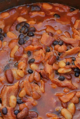 Slow Cooker Baked Beans is made with 4 types of beans simmered with brown sugar, bacon, and more! An Easy Baked Bean recipe the whole family will love. #bakedbeansrecipe #homemadebakedbeans #crockpotbakedbeans www.savoryexperiments.com