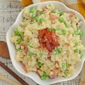 Creamy Parmesan Risotto takes the most traditional risotto recipe and adds vibrant peas and crispy bacon. Sauteed in bacon fat, this rice packs a flavor punch! #parmesanrisottorecipe #easyrisottorecipe www.savoryexperiments.com