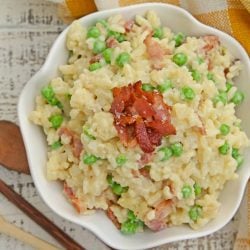 Creamy Parmesan Risotto takes the most traditional risotto recipe and adds vibrant peas and crispy bacon. Sauteed in bacon fat, this rice packs a flavor punch! #parmesanrisottorecipe #easyrisottorecipe www.savoryexperiments.com