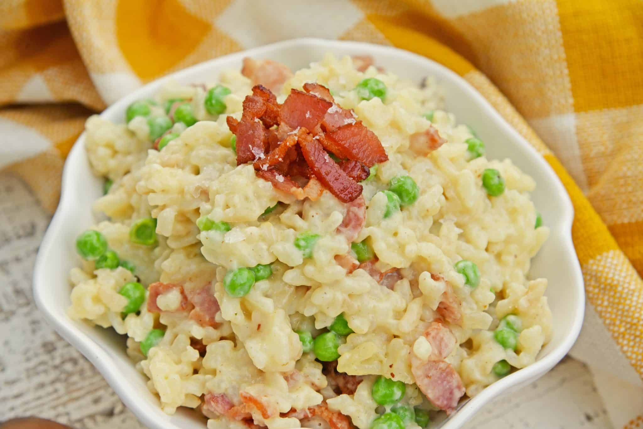 Creamy Parmesan Risotto takes the most traditional risotto recipe and adds vibrant peas and crispy bacon. Sauteed in bacon fat, this rice packs a flavor punch! #parmesanrisottorecipe #easyrisottorecipe www.savoryexperiments.com
