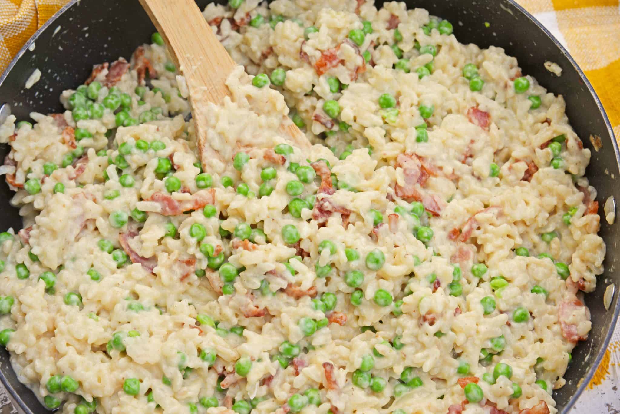 Creamy Parmesan Risotto takes the most traditional risotto recipe and adds vibrant peas and crispy bacon. Sauteed in bacon fat, this rice packs a flavor punch! #parmesanrisottorecipe #easyrisottorecipe www.savoryexperiments.com
