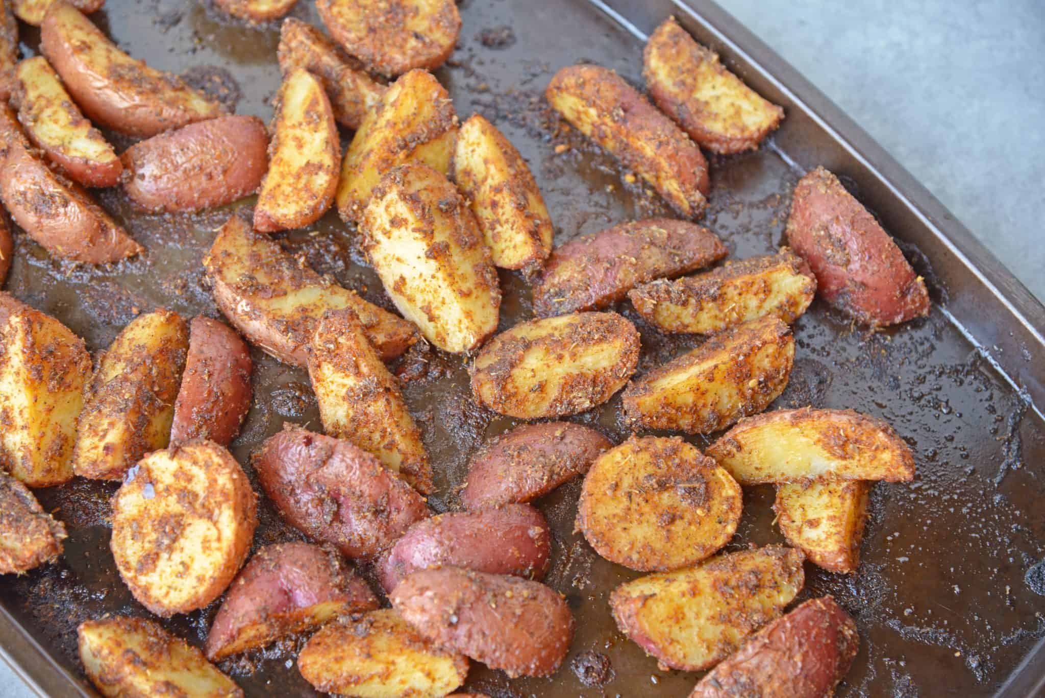 These Spicy Baked Potato Wedges are the best side dish to serve with a juicy hamburger. Tossed in a zesty spice blend, they are baked to crispy perfection.#seasonedpotatowedges #bakedpotatowedges www.savoryexperiments.com