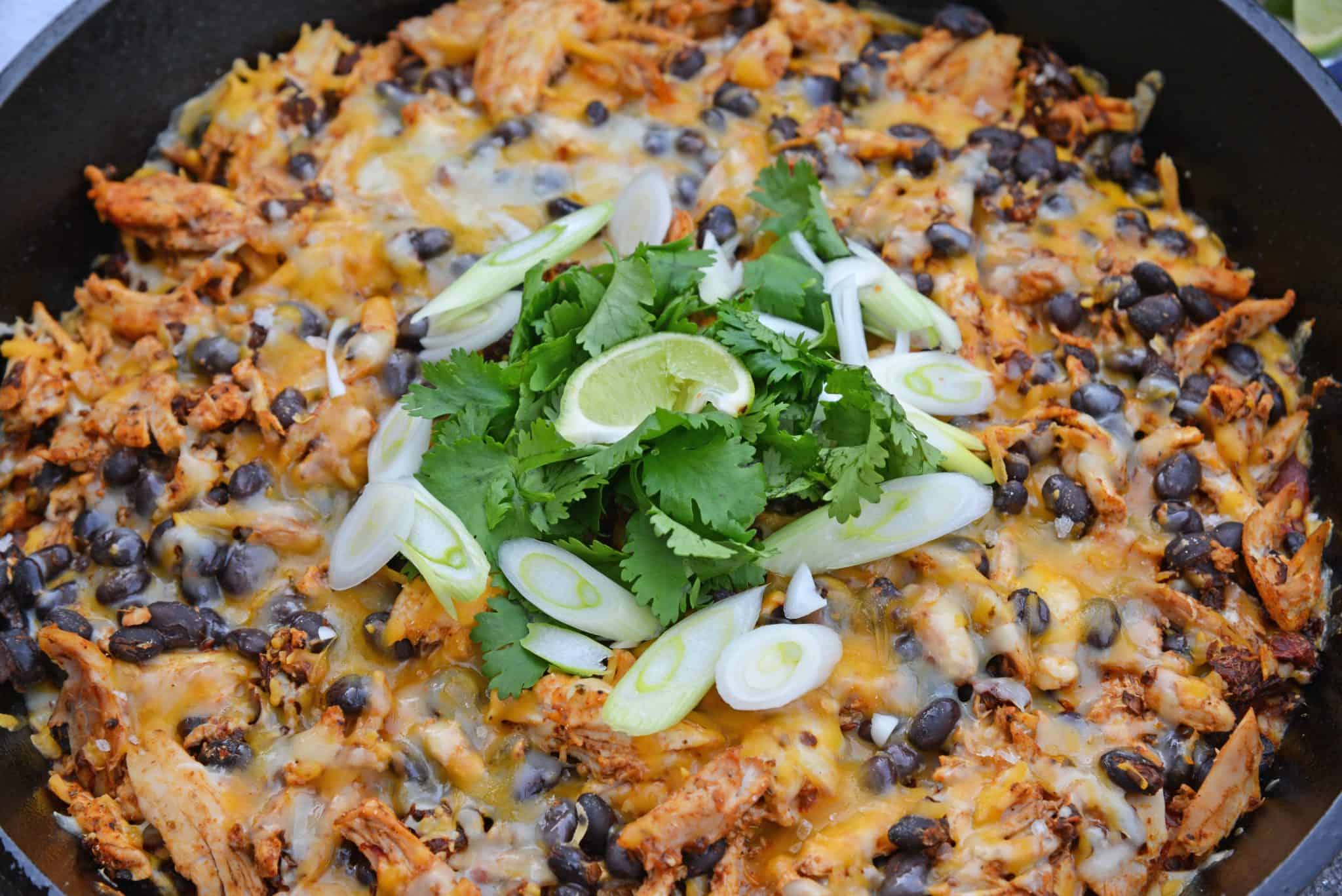 This Chicken Enchilada Casserole Recipe is a delicious casserole recipe loaded with a cornbread crust, chicken, beans, and cheese, all made in a cast iron skillet! #chickenenchiladacasserole #castironskilletrecipes www.savoryexperiments.com