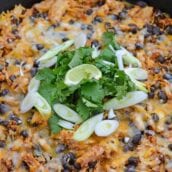 chicken enchilada casserole in cast iron with scallions