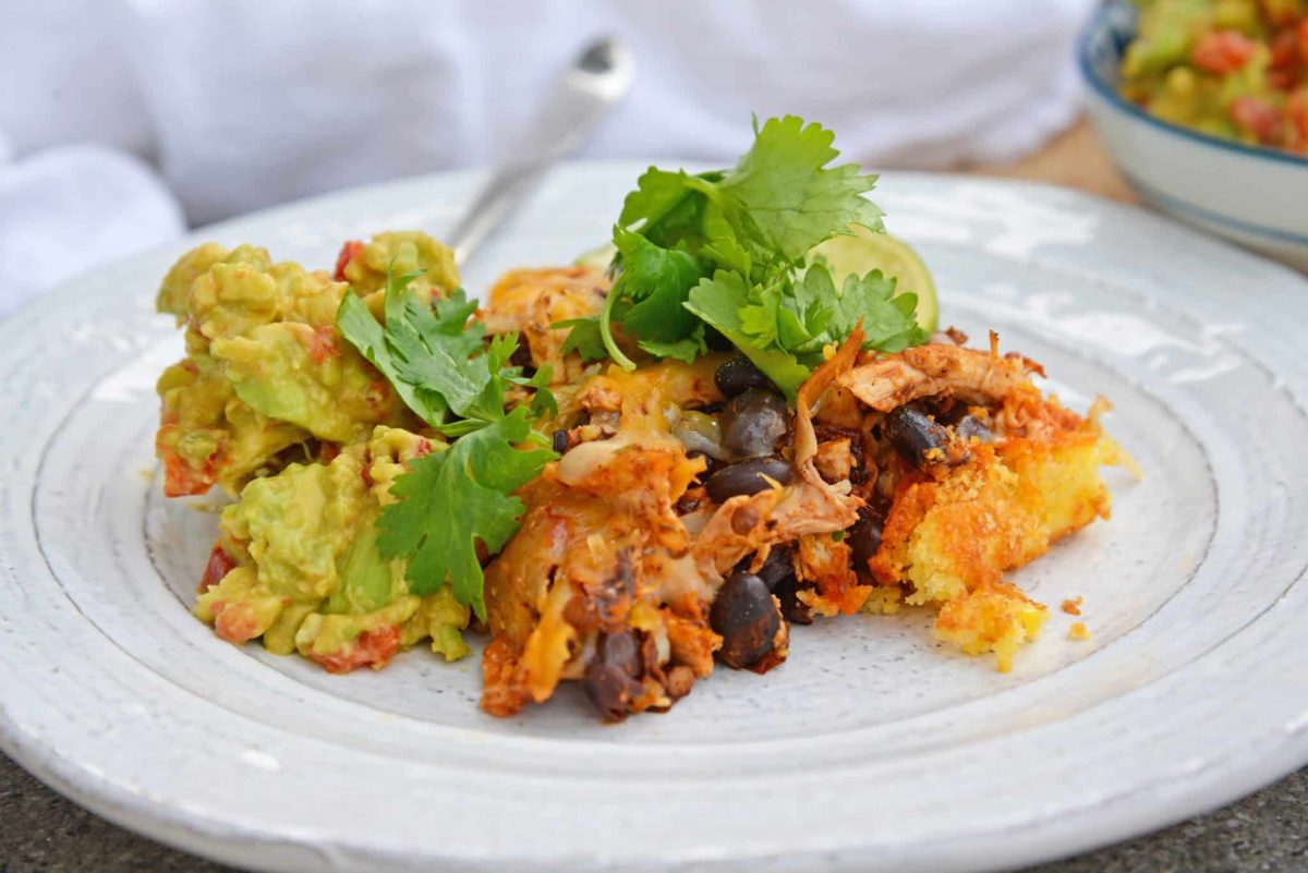 This Chicken Enchilada Casserole Recipe is a delicious casserole recipe loaded with a cornbread crust, chicken, beans, and cheese, all made in a cast iron skillet! #chickenenchiladacasserole #castironskilletrecipes www.savoryexperiments.com