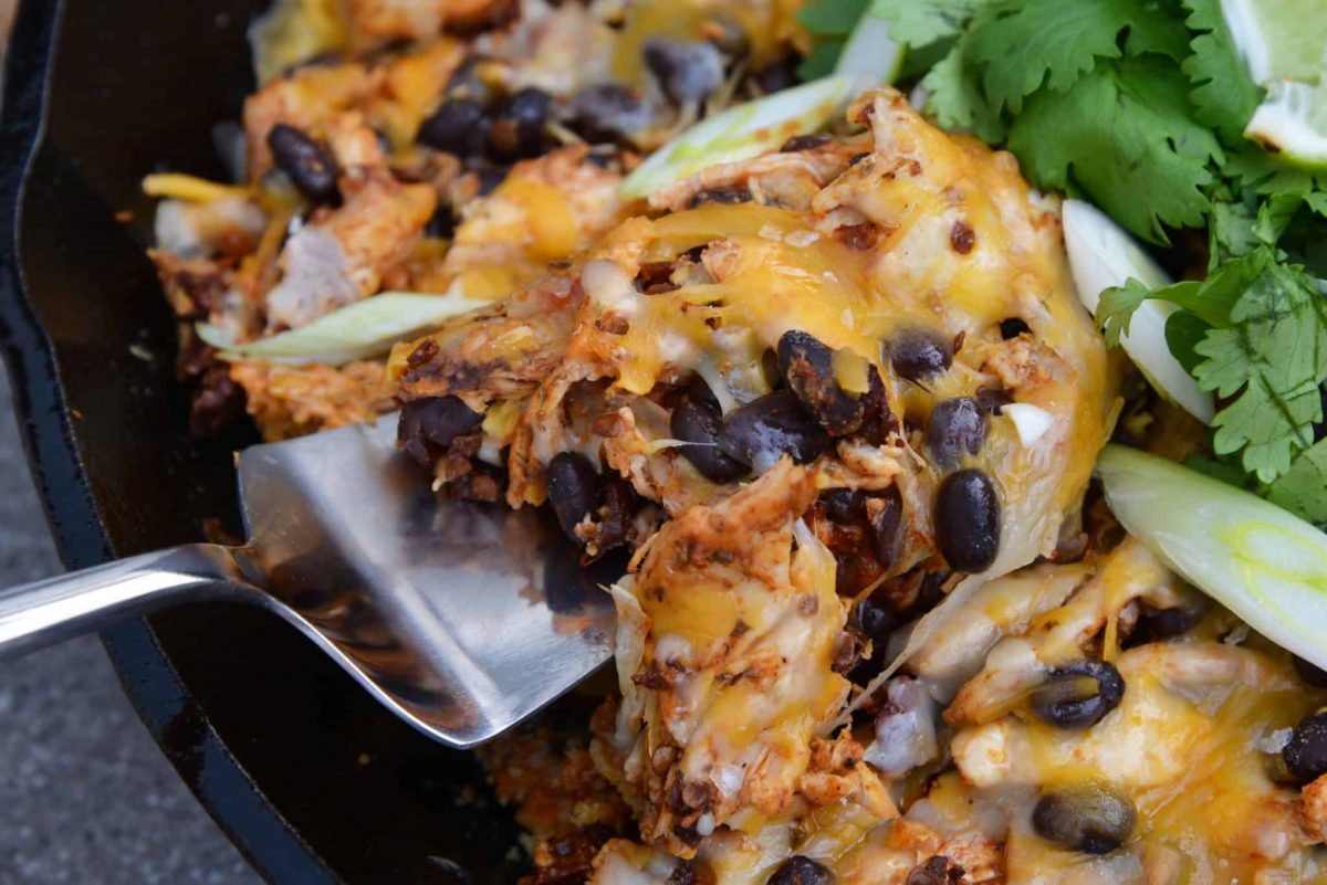 This Chicken Enchilada Casserole Recipe is a delicious casserole recipe loaded with a cornbread crust, chicken, beans, and cheese, all made in a cast iron skillet! #chickenenchiladacasserole #castironskilletrecipes www.savoryexperiments.com