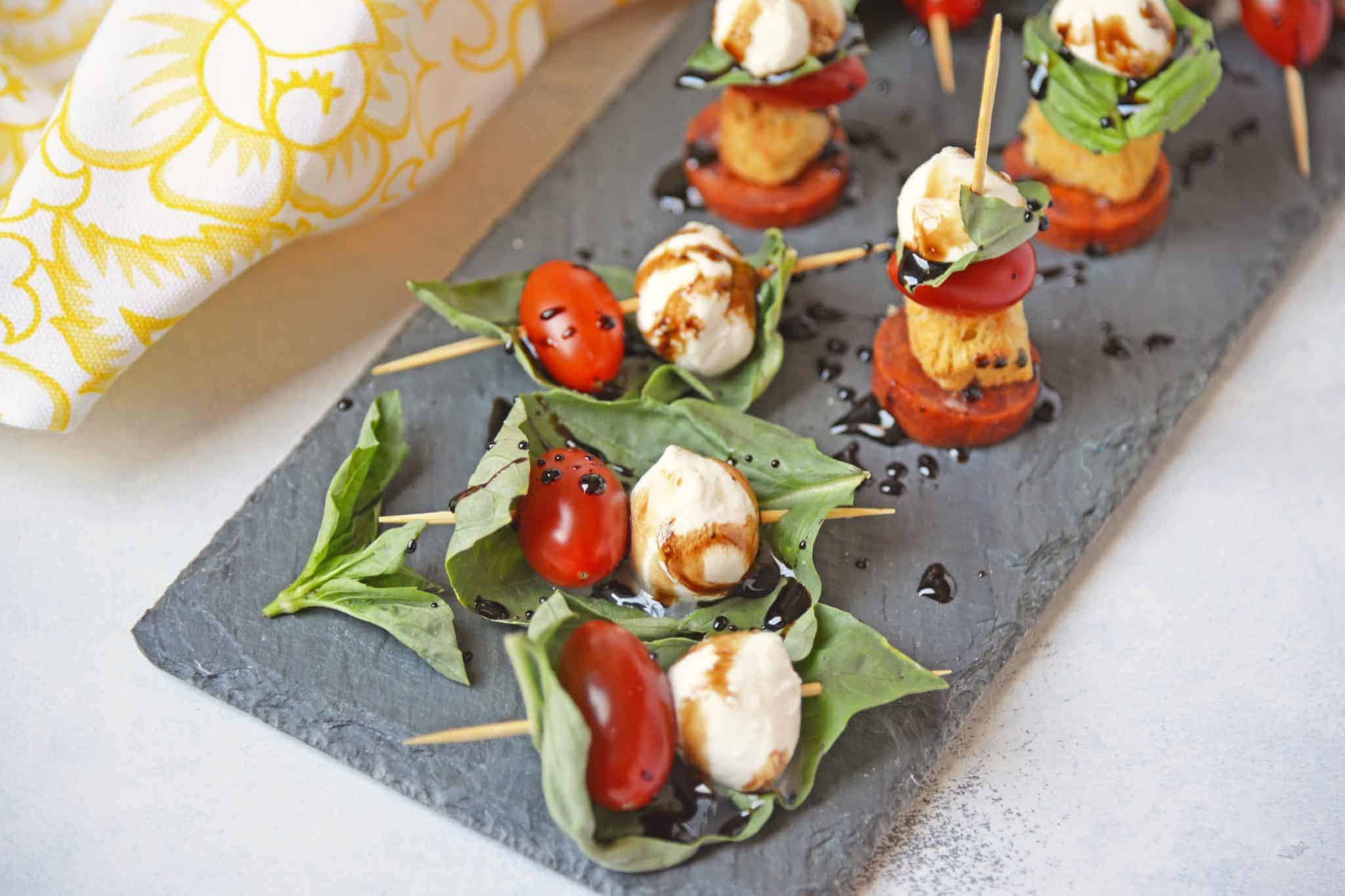 Caprese Skewers are the perfect party appetizer made with fresh mozzarella, basil, tomatoes, garlicky croutons, and zesty pepperoni, all drizzled with a tangy balsamic reduction sauce! #capresesalad #capreseappetizer www.savoryexperiments.com