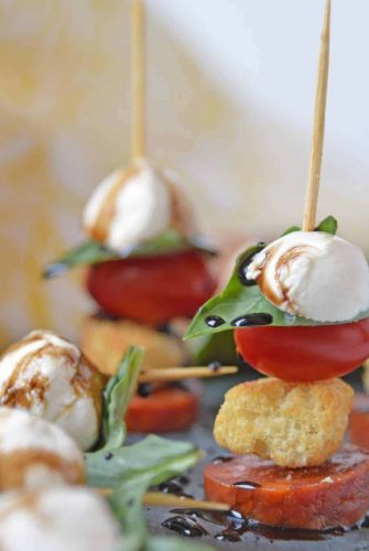 Caprese Skewers are the perfect party appetizer made with fresh mozzarella, basil, tomatoes, garlicky croutons, and zesty pepperoni, all drizzled with a tangy balsamic reduction sauce! #capresesalad #capreseappetizer www.savoryexperiments.com