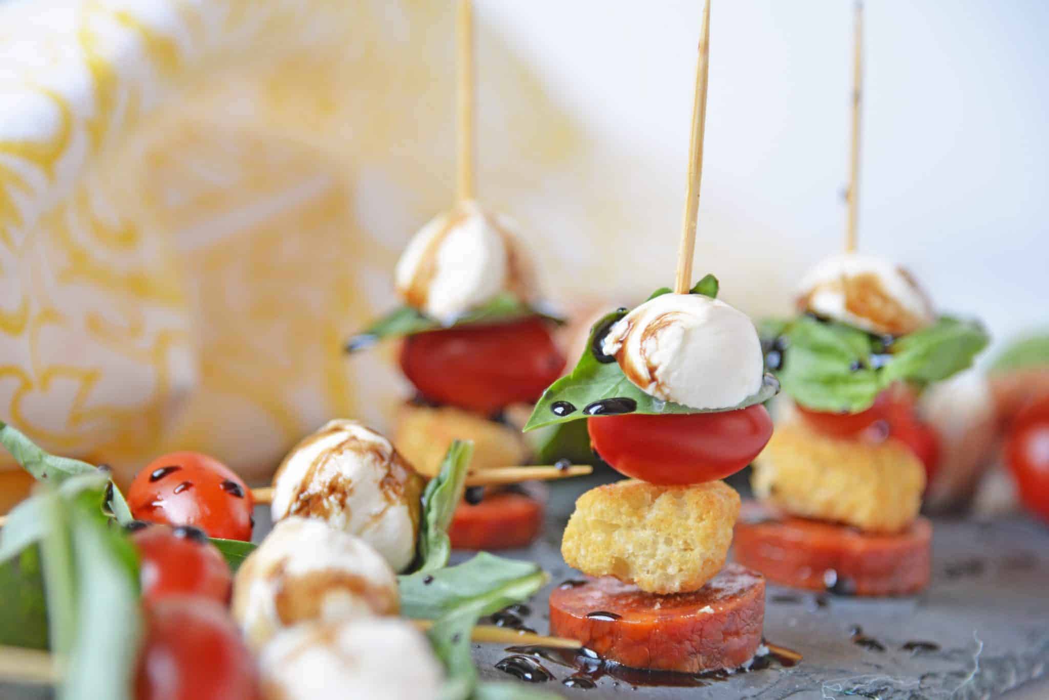 Caprese Skewers are the perfect party appetizer made with fresh mozzarella, basil, tomatoes, garlicky croutons, and zesty pepperoni, all drizzled with a tangy balsamic reduction sauce! #capresesalad #capreseappetizer www.savoryexperiments.com