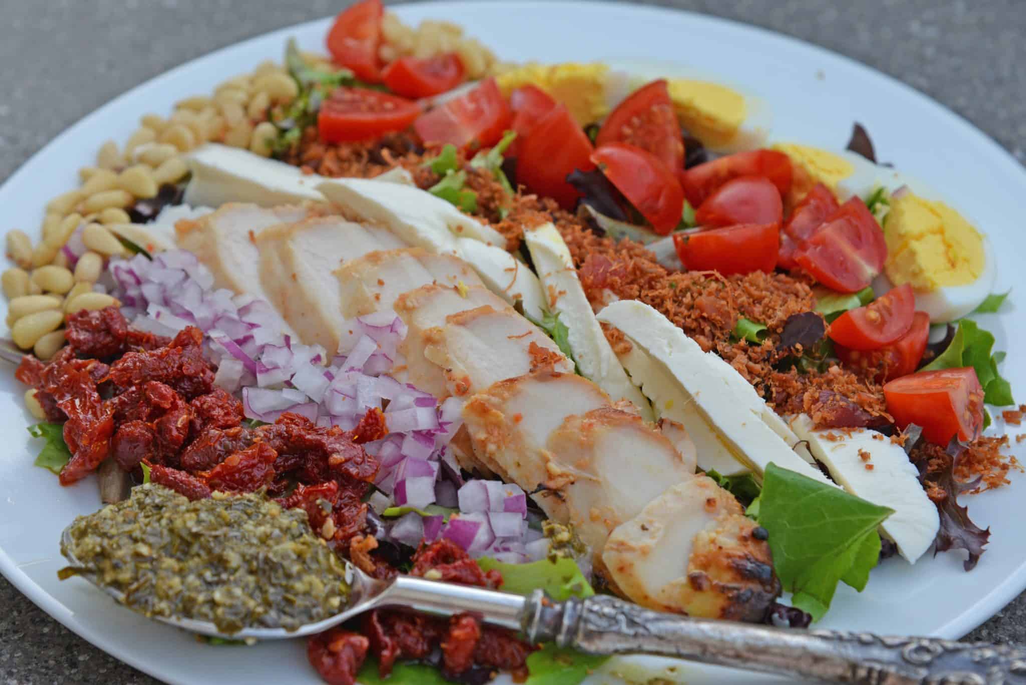 Pesto Chicken Cobb Salad is a delicious salad recipe using traditional Cobb ingredients with chicken and a pesto dressing. The perfect starter or entree! #Cobbsaladrecipe #pestochickensalad www.savoryexperiments.com