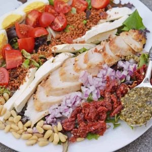 Pesto Chicken Cobb Salad is a delicious salad recipe using traditional Cobb ingredients with chicken and a pesto dressing. The perfect starter or entree! #Cobbsaladrecipe #pestochickensalad www.savoryexperiments.com