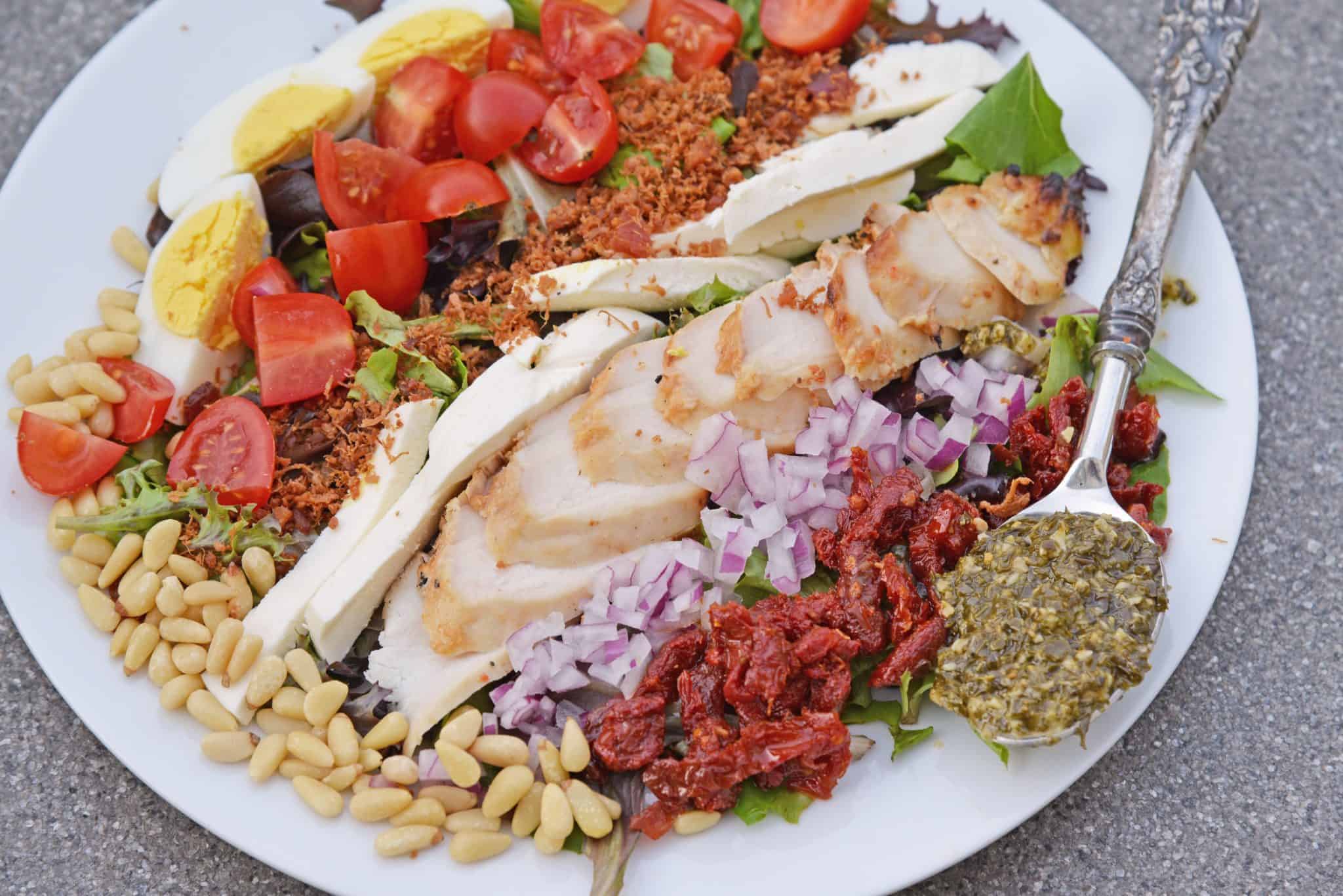 Pesto Chicken Cobb Salad is a delicious salad recipe using traditional Cobb ingredients with chicken and a pesto dressing. The perfect starter or entree! #Cobbsaladrecipe #pestochickensalad www.savoryexperiments.com