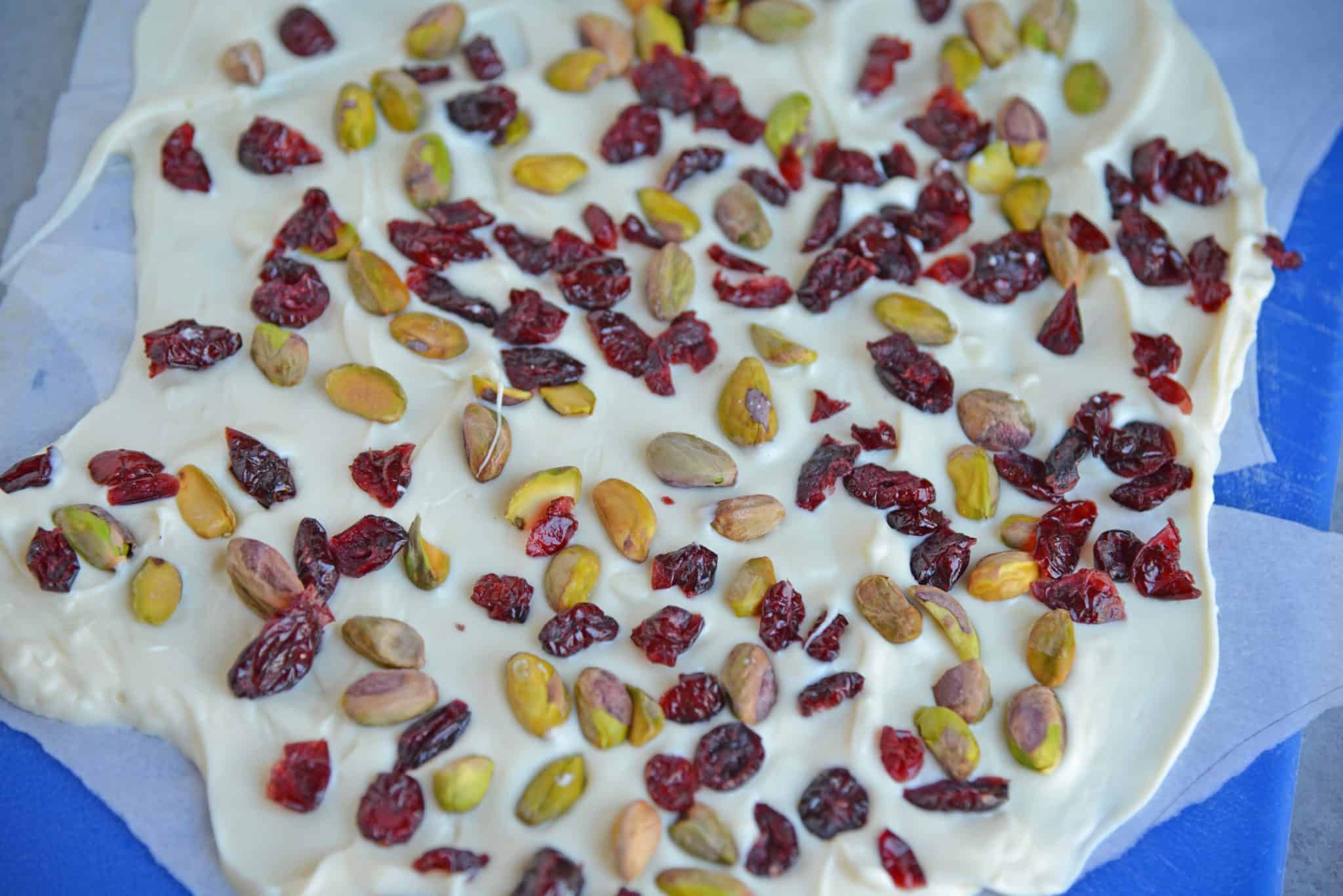 Pistachio Cranberry Bark is a delicious combination of pistachios, cranberries, and white chocolate! Perfect for the holiday season with its festive colors! #christmasbarkrecipe #pistachiocranberrybark www.savoryexperiments.com