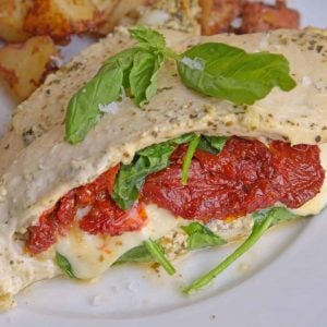 Pesto Spinach Stuffed Chicken are chicken breasts stuffed with gooey mozzarella cheese, sun dried tomatoes and spinach. Marinated in a yogurt and basil pesto sauce, they are moist and flavorful. #stuffedchicken #spinachstuffedchicken www.savoryexperiments.com