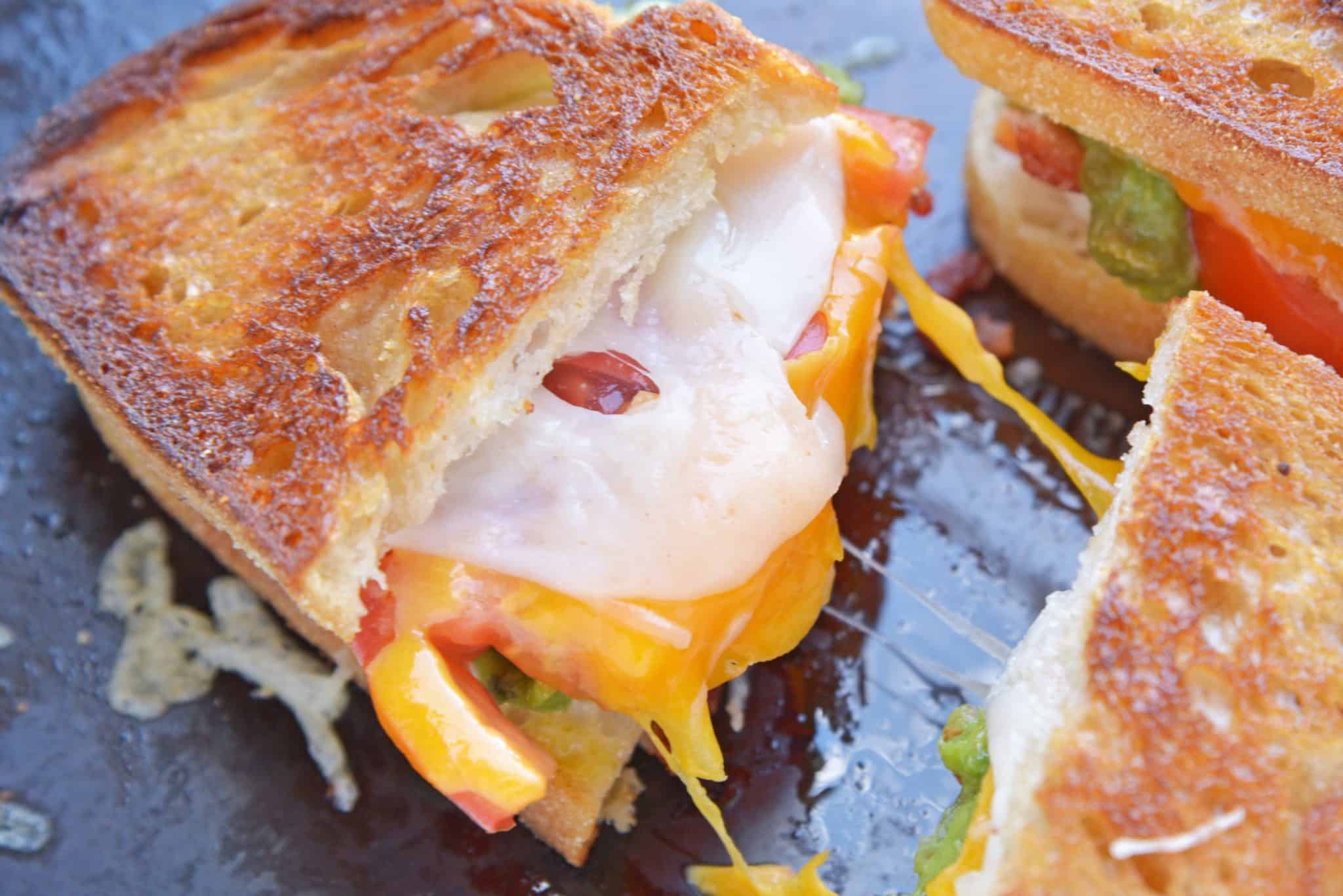 Bacon Avocado Grilled Cheese Sandwiches are made from a three cheese blend along with zesty guacamole, lime, and bacon, for out of this world sandwich experience! #howtomakegrilledcheese #gourmetgrilledcheese #avocadogrilledcheese www.savoryexperiments.com