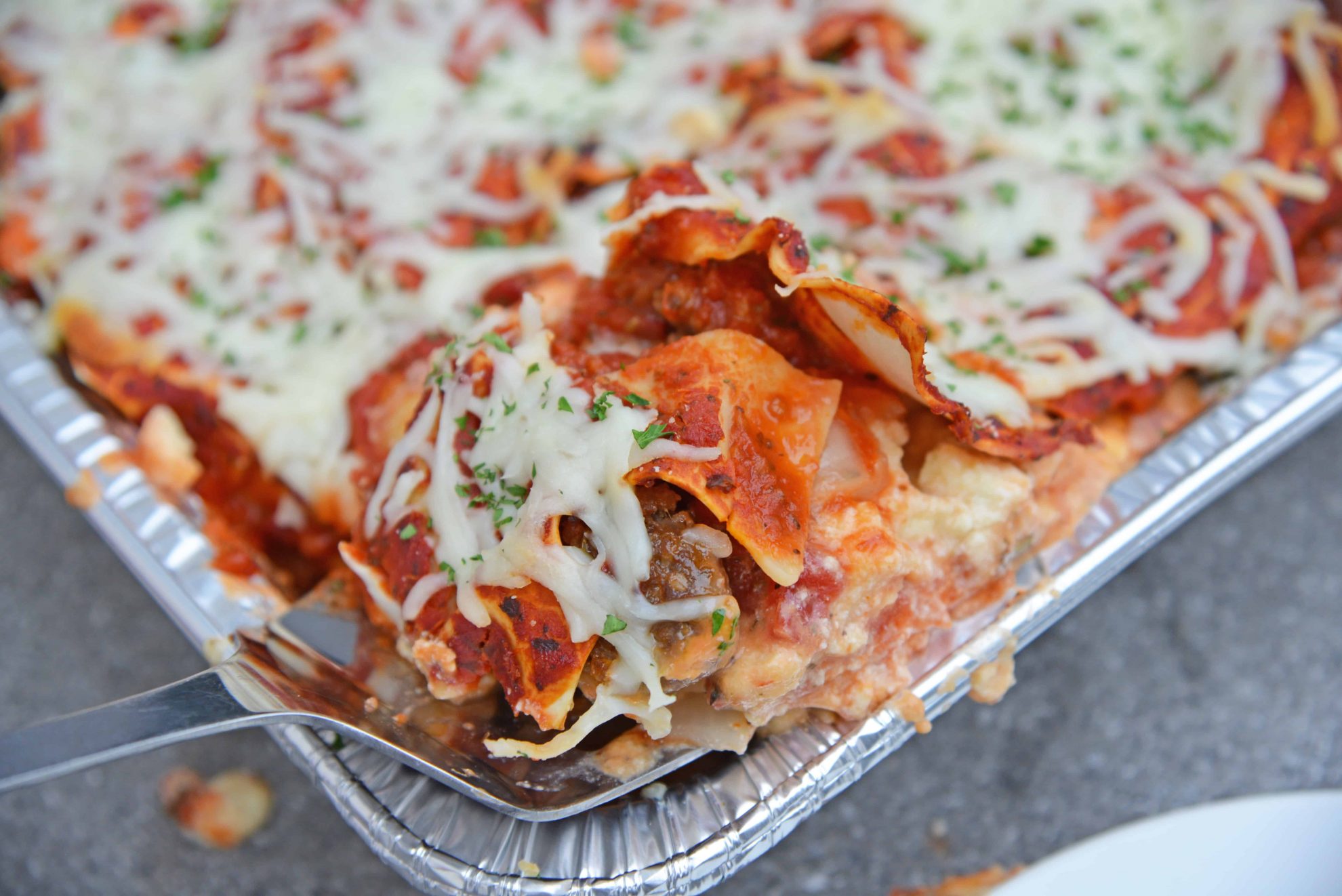 spatula spooning out a large portion of lasagna for a crowd