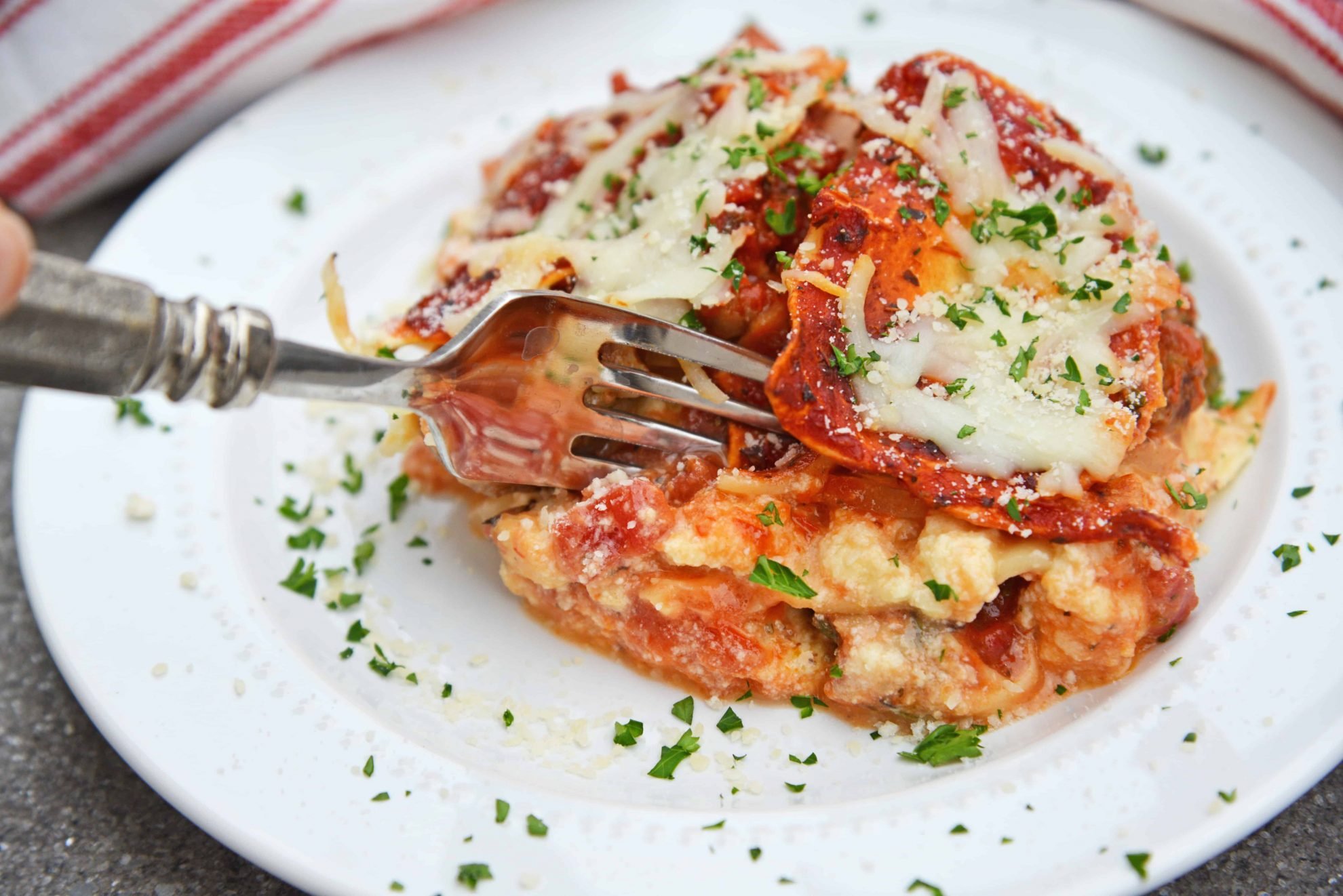 fork digging into no boil lasagna on a white plate