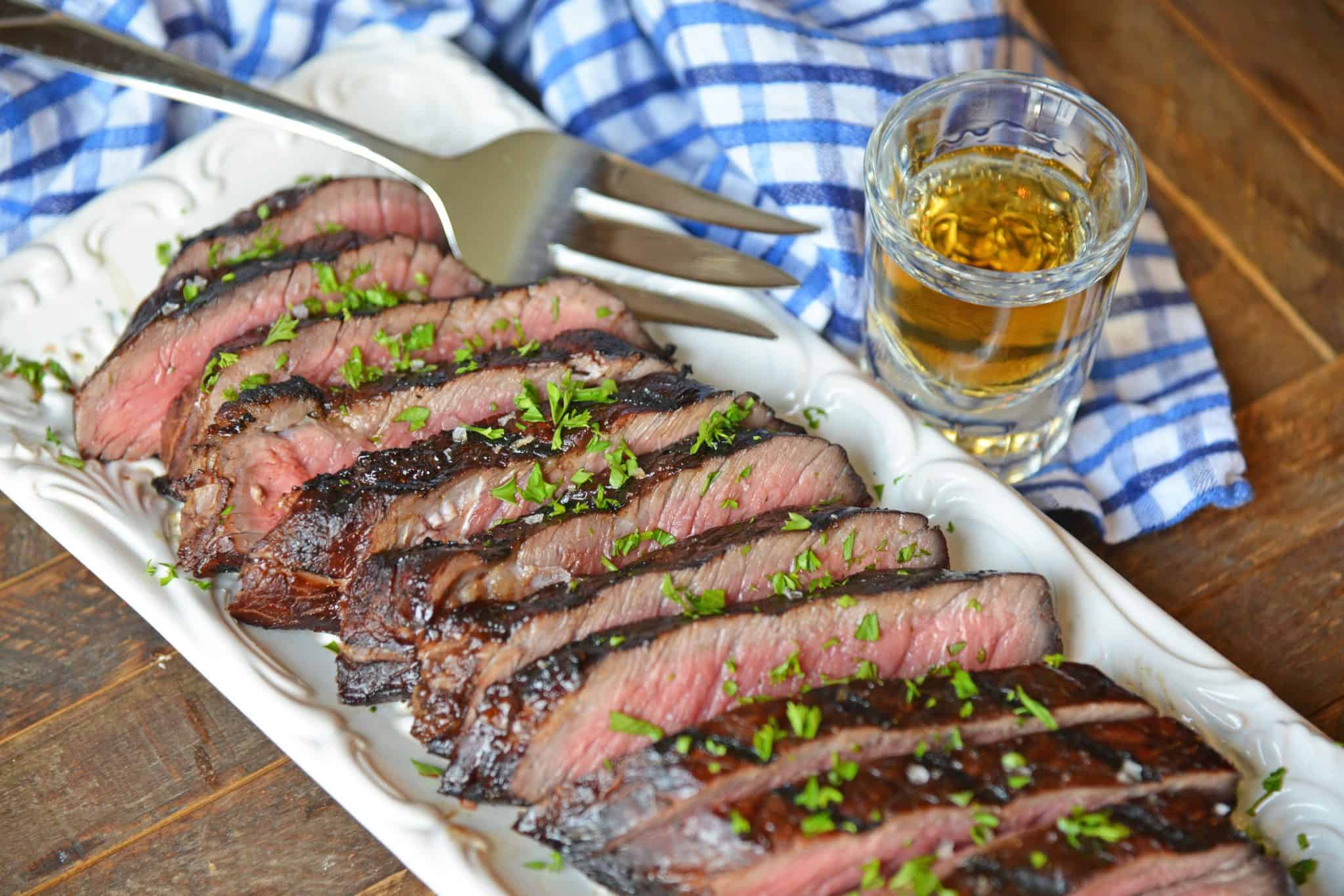 sliced juicy sirloin steak marinade with a serving fork and blue linen