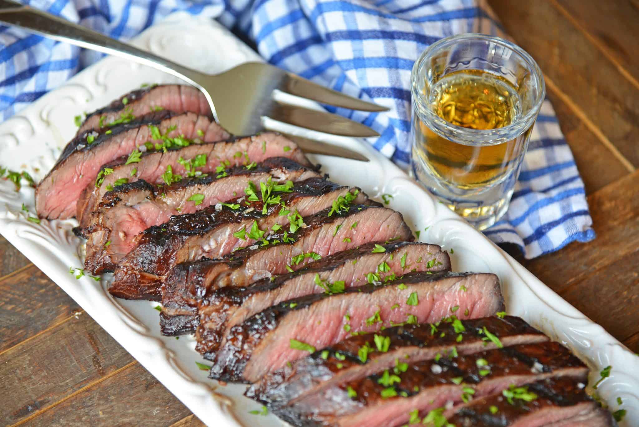 sliced juicy sirloin steak marinade with a serving fork and blue linen 