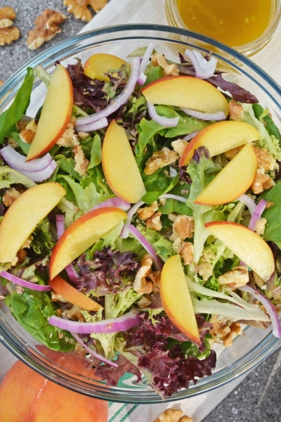 Peach Salad is a scrumptious summer salad filled with delicious peaches, gorgonzola cheese, shallots, candied walnuts and a tangy peach dressing. The perfect summer salad! #peachsalad #summersalads www.savoryexperiments.com
