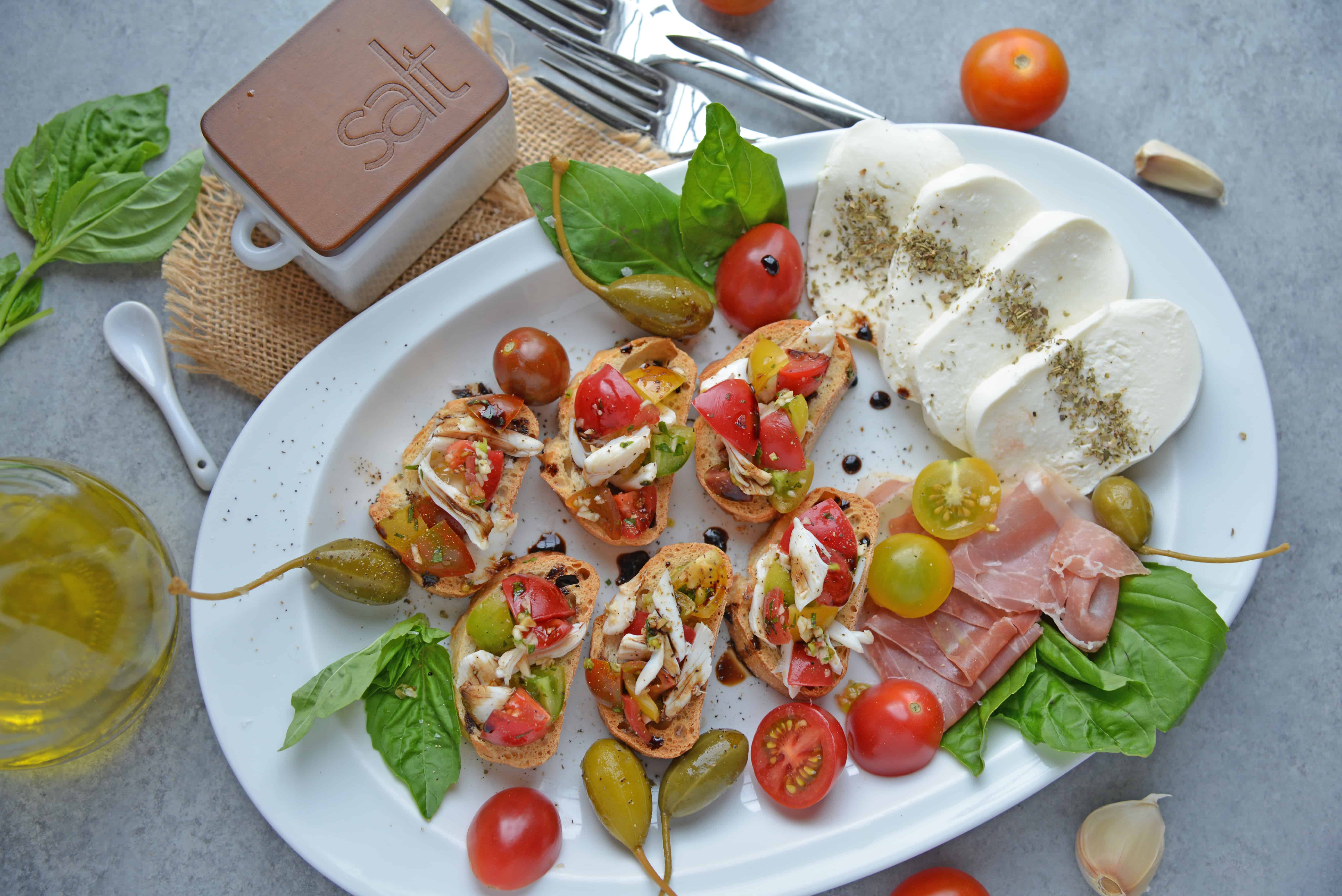 Crab Bruschetta is a mound of fresh tomatoes, garlic basil and buttery crab meat piled high on crispy toast. This is one of the best appetizers out there! #crabbruschetta #easybruschetta www.savoryexperiments.com