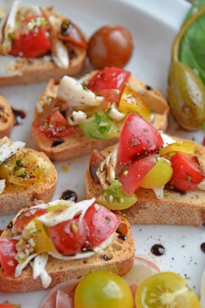 Crab Bruschetta is a mound of fresh tomatoes, garlic basil and buttery crab meat piled high on crispy toast. This is one of the best appetizers out there! #crabbruschetta #easybruschetta www.savoryexperiments.com